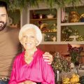 Mary Berry and friend Rylan smiling for camera. Christmas holiday decorations behind them