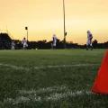 High School football teams line up for kickoff while the sun sets.