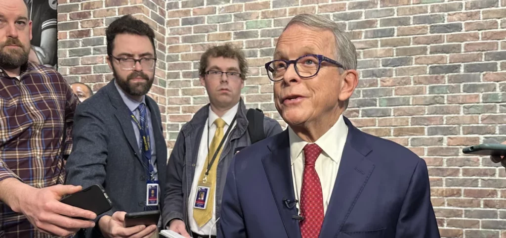 Gov. Mike DeWine talking to members of the media who hold out recorders and cellphones