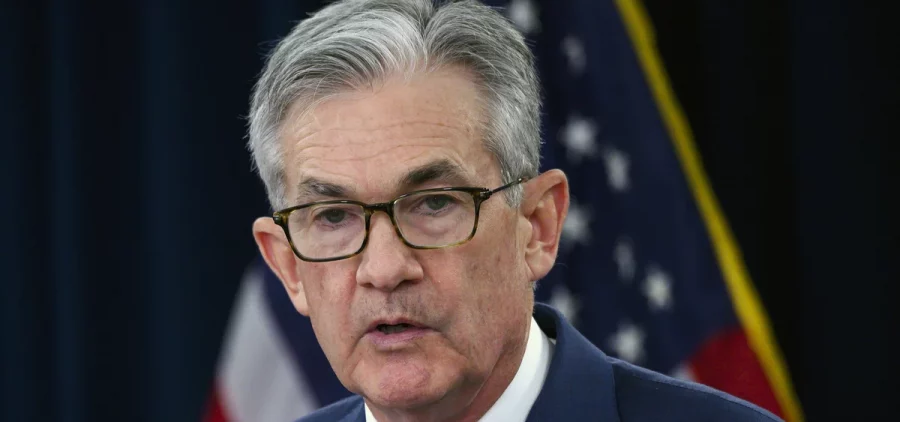 Jerome Powell is interviewed by reporters at a podium.