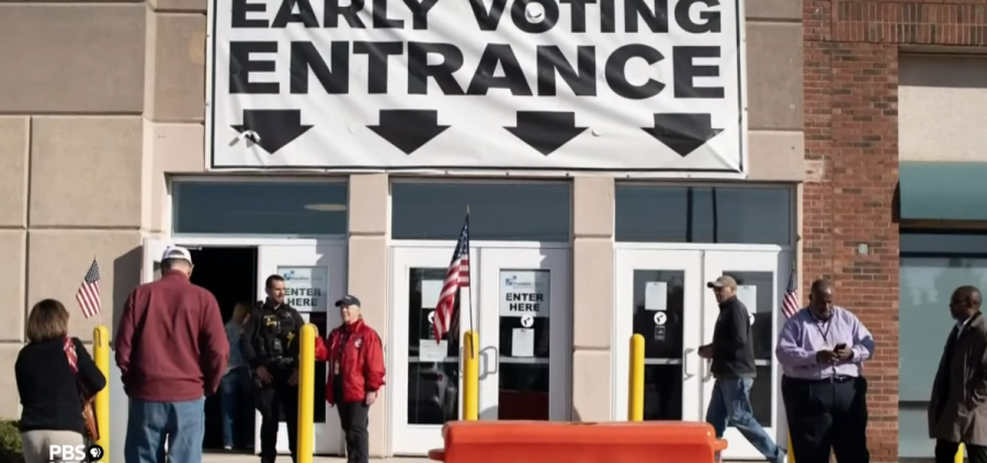 People approach a series of double doors with the sign "early voting entrance" above them.