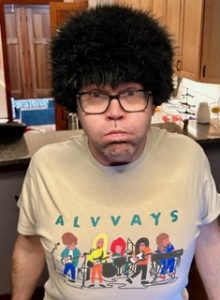An image of a man in a goofy wig and an Alvvays t-shirt