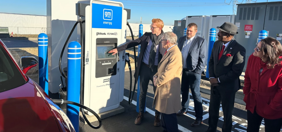 Governor Mike DeWine stands with a small crowd watching a man showing off the new charging station.