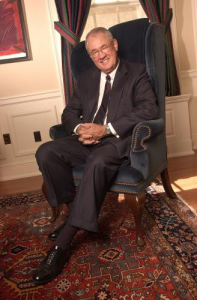 Dr. Robert Glidden sits in an upholstered chair and smiles at the camera.