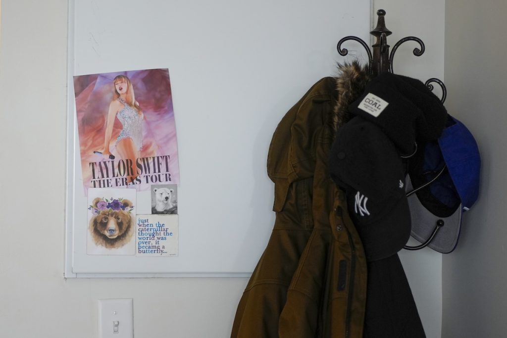 A poster of Taylor Swift and a smaller sign that reads, "just when the caterpillar thought the world was over, it became a butterfly…." Next to the coat rack in Ashton Colby's apartment in Columbus.