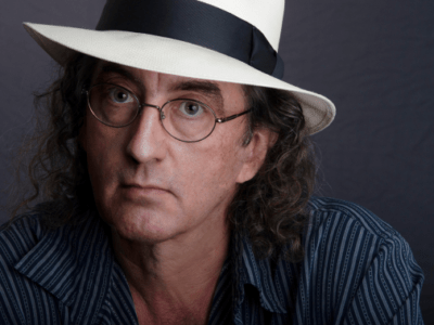 A promotional headshot of musician James McMurty. He is wearing a white cowboy hat.