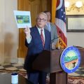 Gov. Mike DeWine at a December press conference holding an advertisement for a business selling unregulated hemp products.