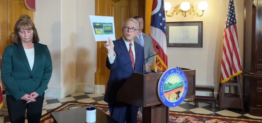 Gov. Mike DeWine at a December press conference holding an advertisement for a business selling unregulated hemp products.