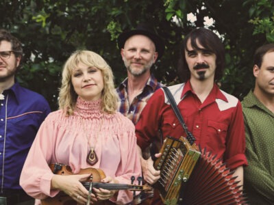 A promotional image of Feufollet, a musical group. The band is posed outside.
