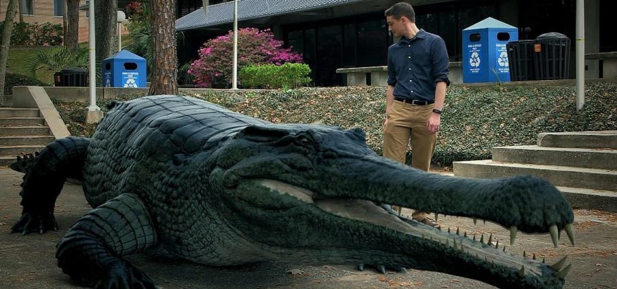 man walking outside next to huge crocodile statue