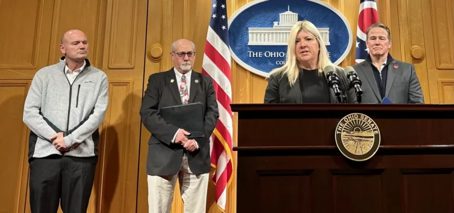 Sens. Stephanie Kunze and Bill DeMora (center) stand near a podium to talk about their proposal to require online sites with adult content, including porn, to verify Ohio users' ages and identities with Lt. Gov. Jon Husted and another man looking on.