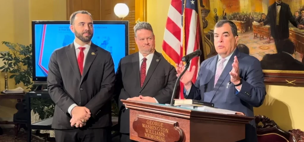 Reps. Adam Mathews (R-Lebanon) and Brian Lampton (R-Beavercreek) watch as Sen. George Lang (R-West Chester) talks to reporters at a press conference on a proposal to eliminate the state income tax and the commercial activity tax.