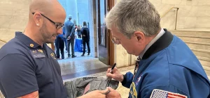 Former astronaut Don Thomas signs Kevin Seymour's bookbag filled with signatures of astronauts.