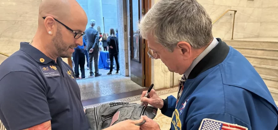 Former astronaut Don Thomas signs Kevin Seymour's bookbag filled with signatures of astronauts.