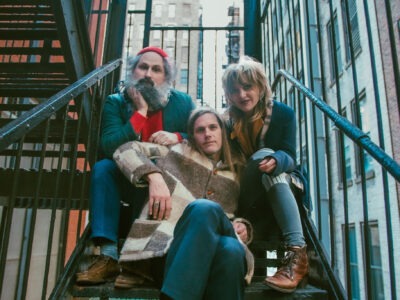 A promotional image of the band Bonny Light Horseman. The band is posing on stairs that are outdoors.