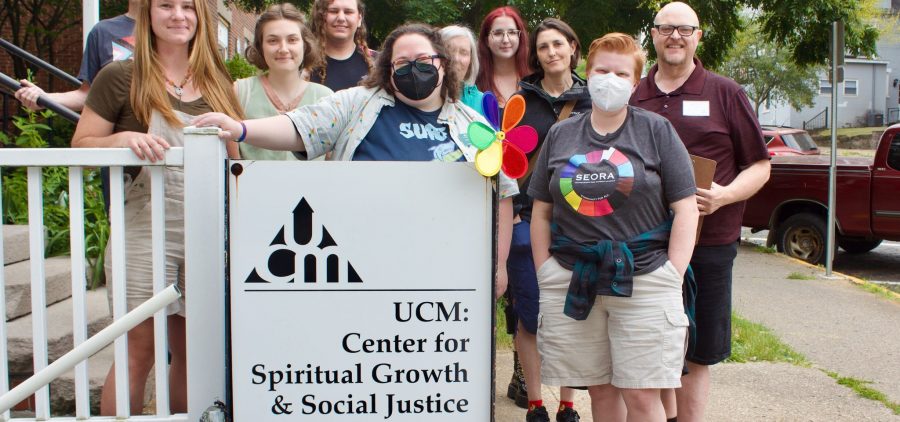 An image of people with a sign for UCM outside.