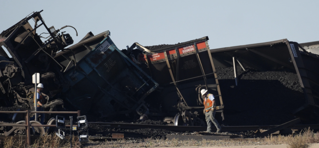 A worker walks by a derailed train.