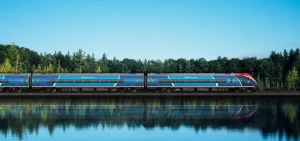 The Amtrak Airo train travels by a lake in the forest
