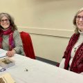 An image of authors Wendy McVicker and Cathy Cultice Lentes seated at an event for their book, "Stronger When We Touch."