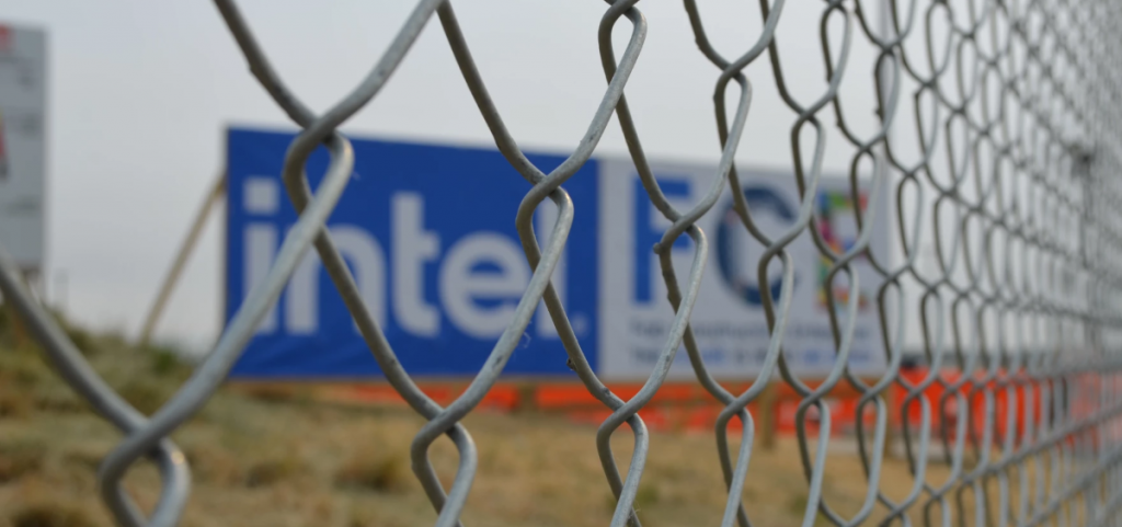 A sign for an Intel plant is visible through a chain link fence.