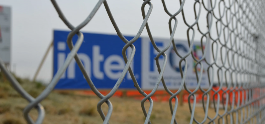 A sign for an Intel plant is visible through a chain link fence.