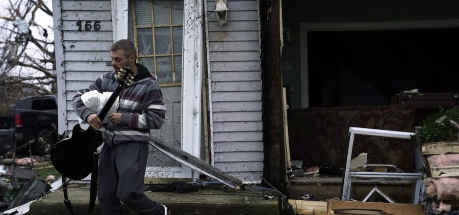 Blaine Schmidt holds his guitar near his damaged home following a severe storm Friday, March 15, 2024, in Lakeview, Ohio.