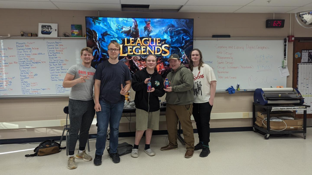 William Dodd, Brandon Almas, Levi Kramer, Clayton Ferguson and Owen White pose in front of a classroom screen displaying the League of Legends title.