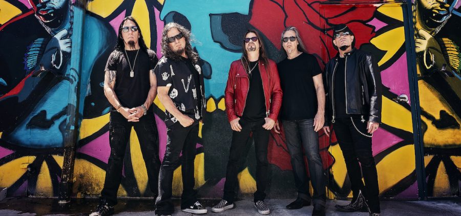 A promotional image of the band Queensryche. They are all posed against a wall of graffiti.