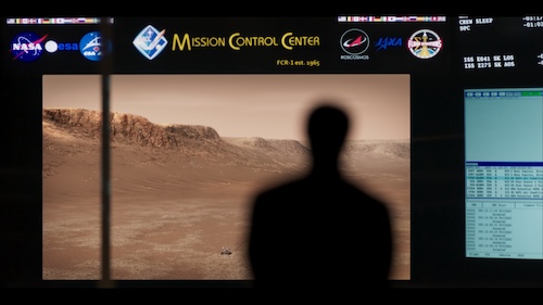 A silhouette at NASA's mission control, overlooking an image of one of the Mars rovers. Credit: Boaz Freund