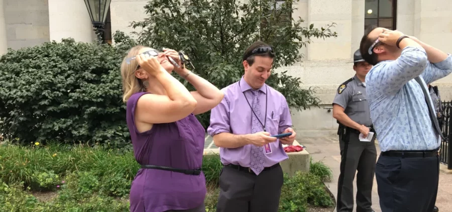 News reporters stand outside the Ohio Statehouse, trying to catch a glimpse of the partial solar eclipse in 2017