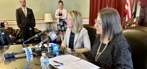 House Minority Leader Allison Russo (D-Upper Arlington) and Senate Minority Leader Nickie Antonio (D-Lakewood) talk to reporters at the Statehouse while seated at a wood table