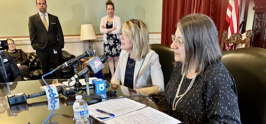 House Minority Leader Allison Russo (D-Upper Arlington) and Senate Minority Leader Nickie Antonio (D-Lakewood) talk to reporters at the Statehouse while seated at a wood table
