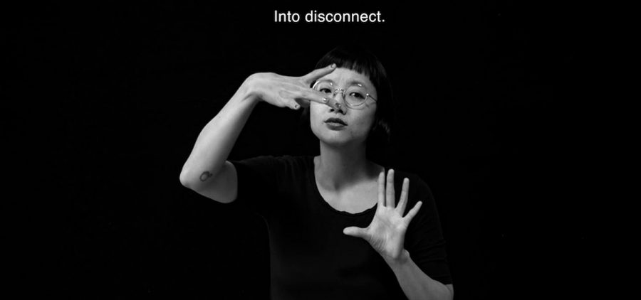 Black background, woman in black dress using sign language, Text abouve her says "Into Disconnect"