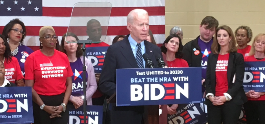 President Joe Biden stands at a podium that reads "BEAT THE NRA WITH BIDEN." Several people hold Biden signs behind him.