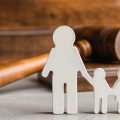A cutout of two adults holding hands with two children stands in front of a gavel.