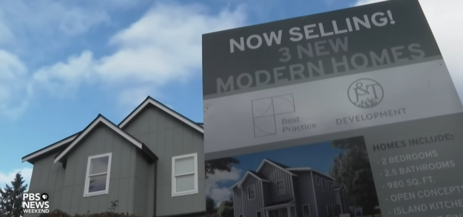 A sign outside a housing development reads, "NOW SELLING! 3 NEW MODERN HOMES"