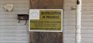 Athens County Land Bank has a sign on a Nelsonville house that says revitalization is in progress. The house will be torn down to create new affordable housing.