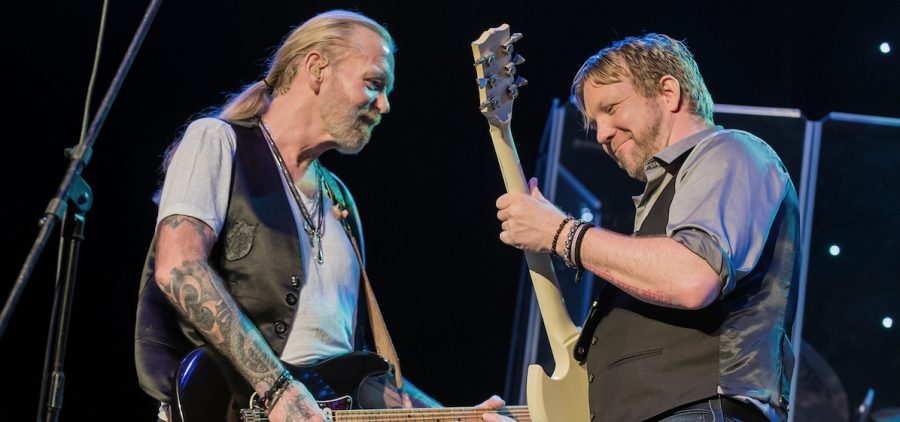 Gregg Allman and band member performing on stage, both playing guitar