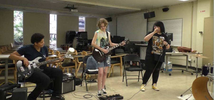 Three girls play instruments at Athens Rock Camp for Girls.