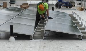 A worker is installing solar panels on the roof of Morrison-Gordon Elementary.