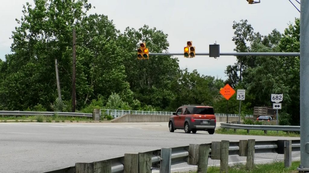 A orange Honda turns right off S.R. 682 on to West Union Street. The stop light is yellow for opposing traffic.