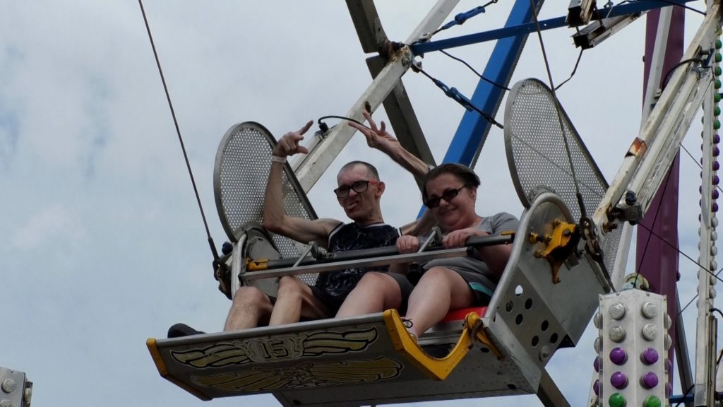 Two people are sitting on the Ferris Wheel at the Lawrence County Fair.