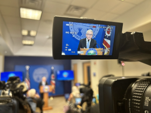 An image of Governor Mike DeWine appears on the view screen of a TV camera during a press conference.