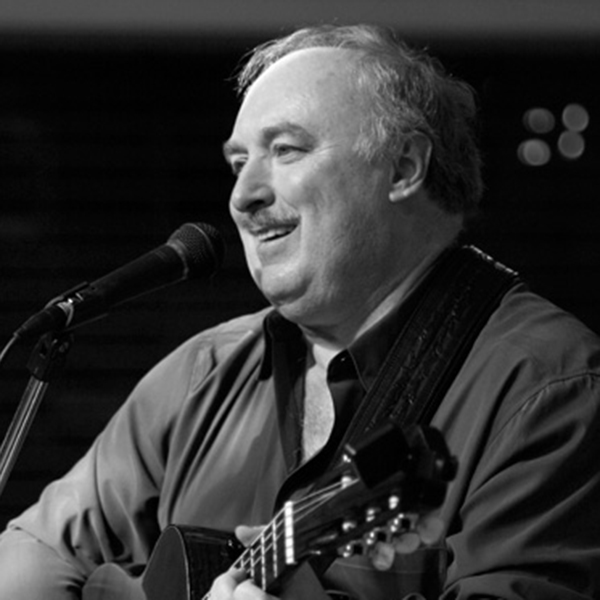 A promotional image of Audie Wykle. It is black and white and he is playing a guitar.