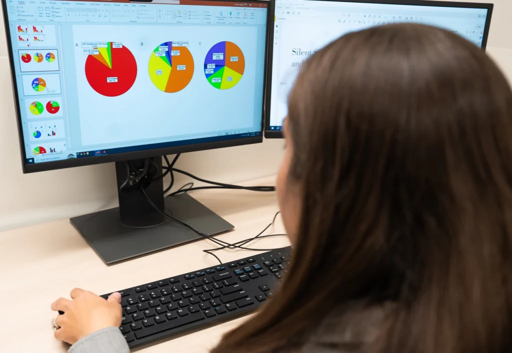 Jaclyn Caccese, PhD, sits at a computer looking over a pie graph of concussion data