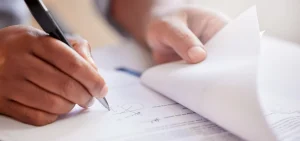 A close-up of a person's hands filling out forms