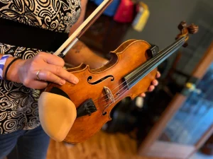 Kerry Varble holds a fiddle and a bow sideways.