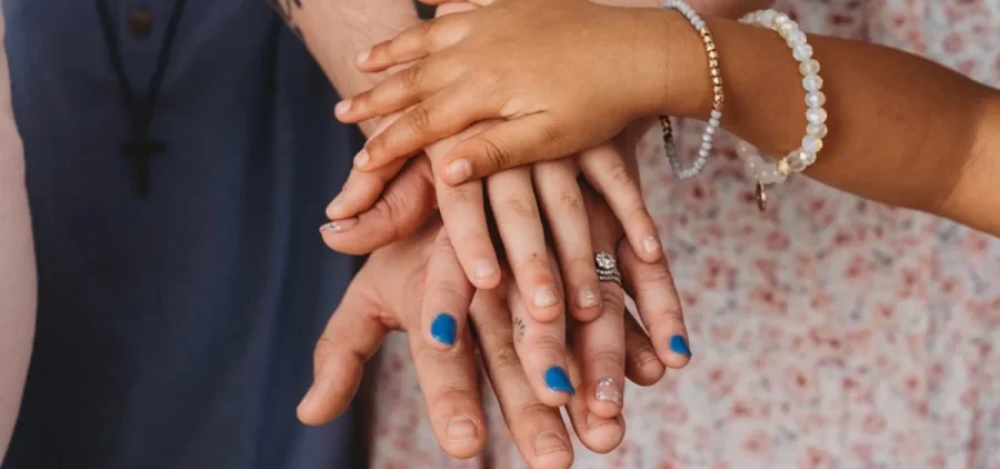 Samantha Stewart and her family pile their hands together for a family picture.