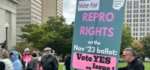 A supporter of Ohio's voter-approved reproductive rights amendment holds a sign outside the Ohio Statehouse