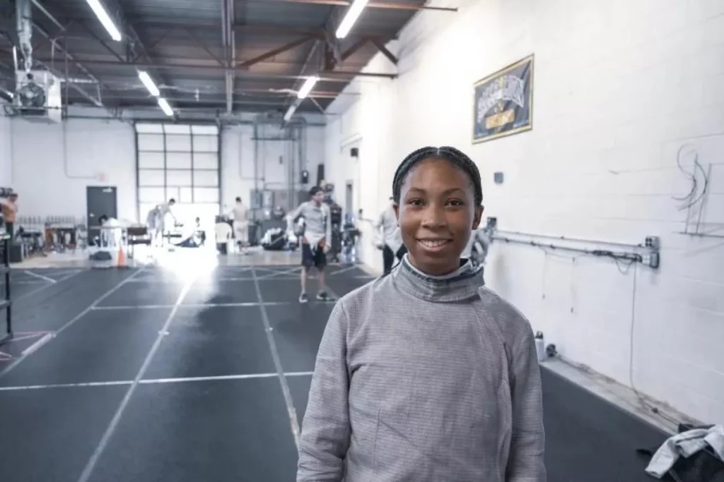 London Waller poses for a portrait in the gym in her fencing gear (without helmet).